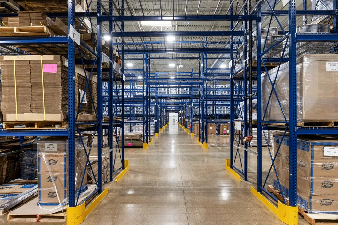 Overhead lights above warehouse racks and an aisle